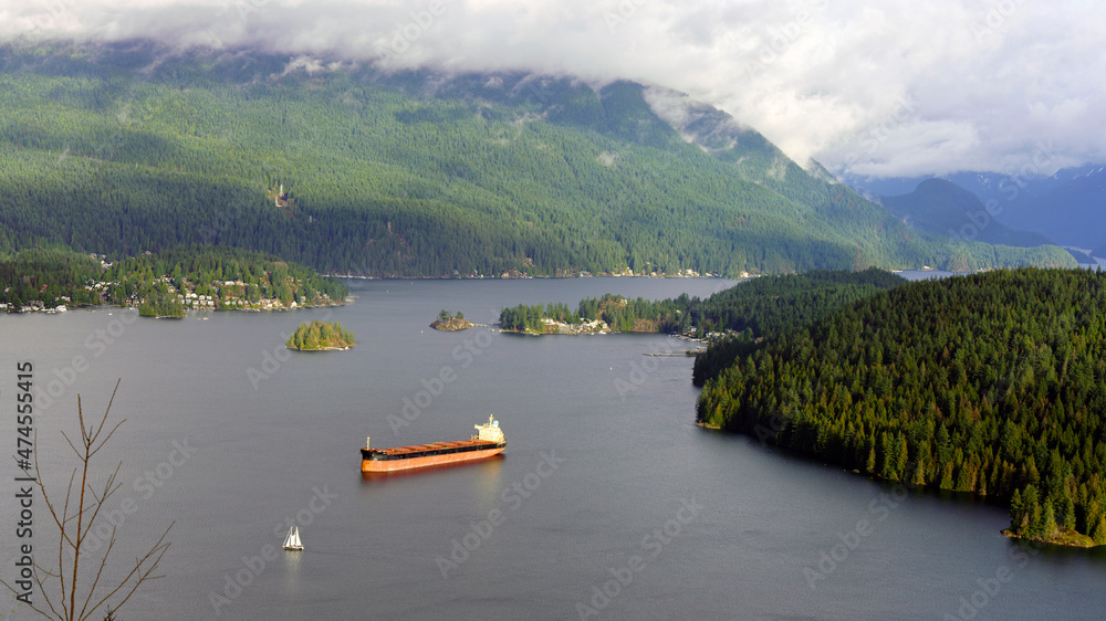 Naklejka premium Placid Burrard Inlet hemmed in by North Shore mountains dear town of Deep Cove in winter with oil tanker and sailboat in foreground.