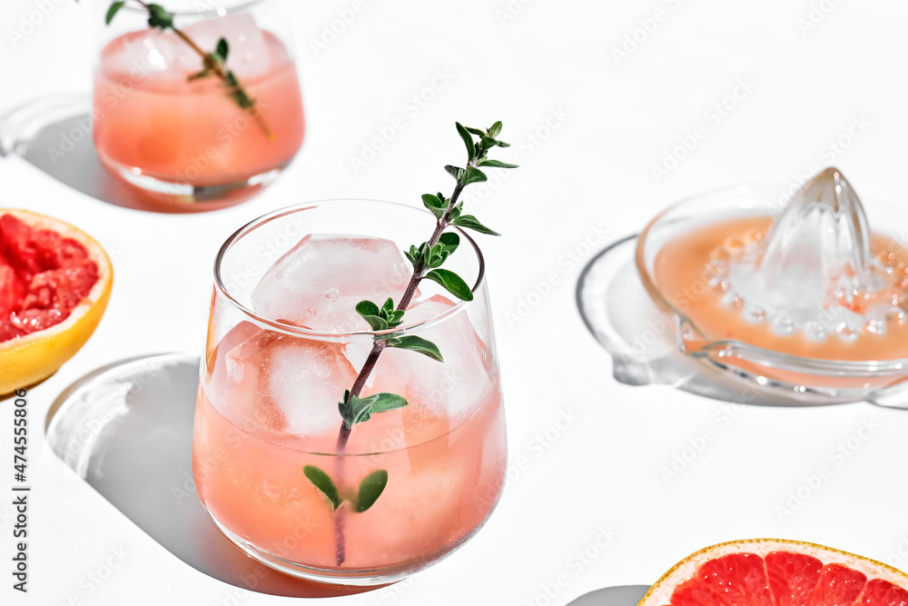 Summer grapefruit cocktail. Fresh healthy grapefruit beverage with herbs on sunlight with hard shadows. Creative drink with palm leaf on light blue pastel background. Summer grapefruit cocktail. Fresh healthy grapefruit beverage with herbs on sunlight with hard shadows. Creative drink with palm leaf on light blue pastel background.