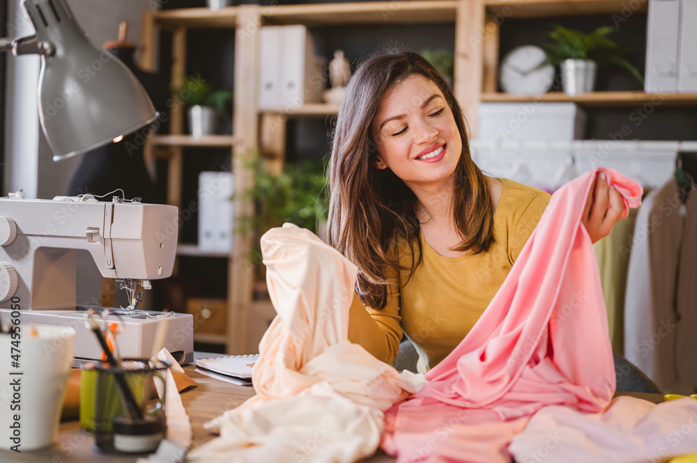 Young smiling entrepreneur woman working in her small workshop. Female small business owner. Young smiling entrepreneur woman working in her small workshop. Female small business owner.