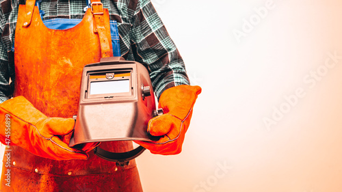 A welder in a protective suit, wearing gloves, holding a welding mask under his arm. Close-up, Note Space, Fiery Colors photo
