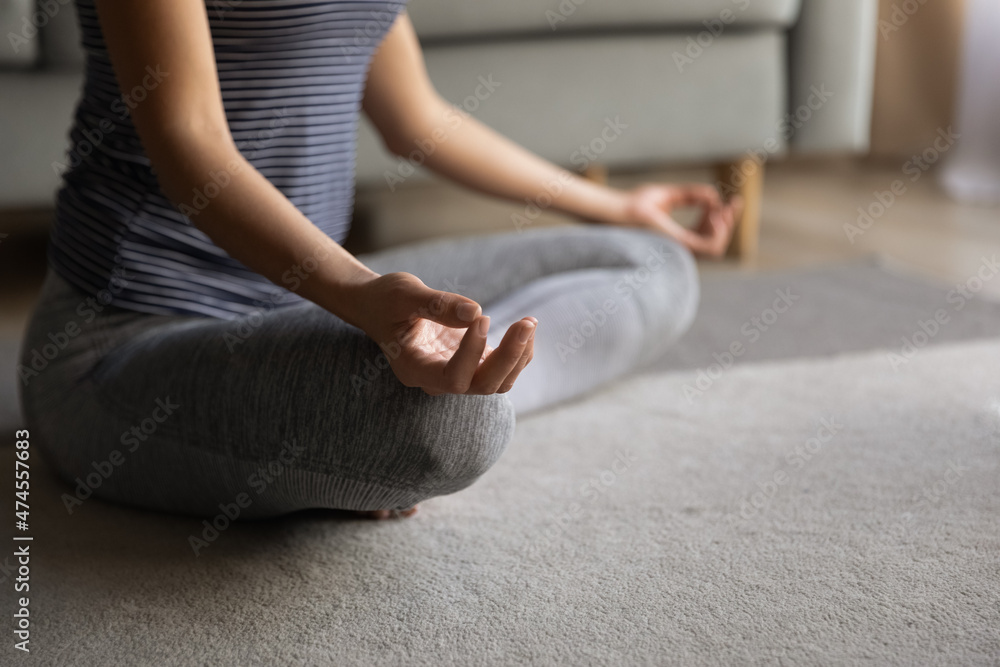 Crop close up of young healthy woman sit on floor with mudra hands practice yoga breathe fresh air. Latin female do morning exercise train meditate at home, relieve negative emotions. Peace concept.