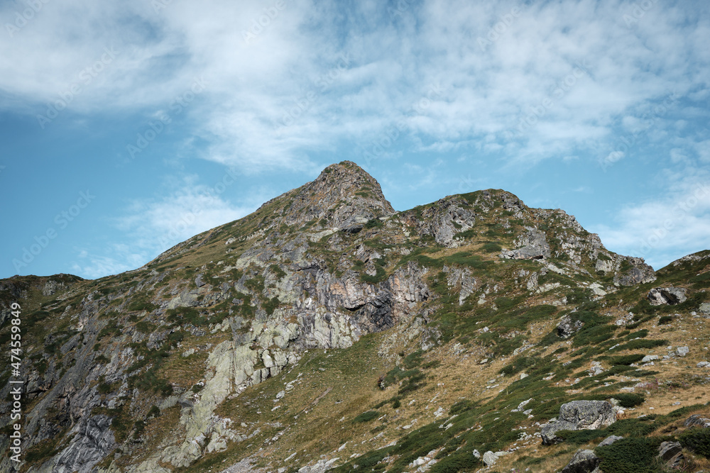 Impressive, pointy, spikey summit on Rila mountain under a blue sky with white clouds smudged by the wind Impressive, pointy, spikey summit on Rila mountain under a blue sky with white clouds smudged by the wind