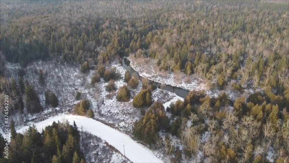 Drone Shot Of Road Surrounded By Coniferous Forest During Winter, Fresh Snow And Creek Drone Shot Of Road Surrounded By Coniferous Forest During Winter, Fresh Snow And Creek