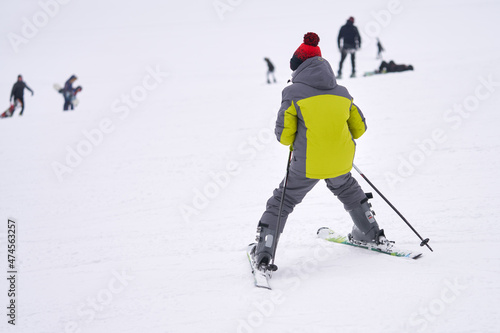 A teenage boy carefully skis down a snow-covered mountainside. He is a novice skier. Copy  space.