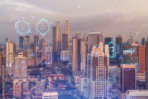 Glowing hologram of technological process, aerial panoramic cityscape of Kuala Lumpur at sunset. KL is the largest innovative hub of tech services in Malaysia, Asia. Multi exposure. photo