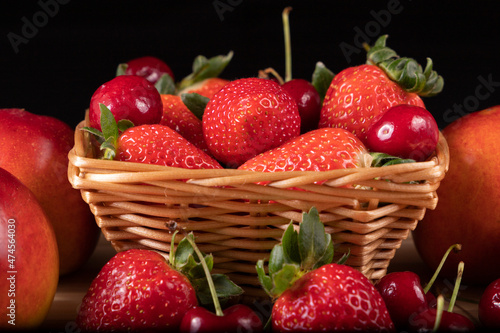 Basket with strawberries and cherries surrounded with nectarines and strawberries.