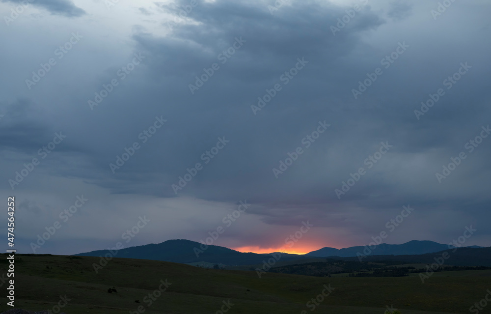 Dramatic sunset behind the mountain. Cloudy sky against the yellow  orange sun. Cloudy sky covering mountain or hill.