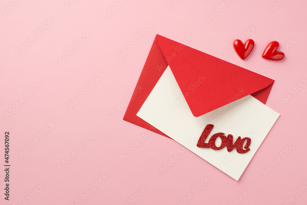 Top view photo of saint valentine's day decorations small hearts red envelope with paper card and inscription love on isolated pastel pink background with empty space Top view photo of saint valentine's day decorations small hearts red envelope with paper card and inscription love on isolated pastel pink background with empty space