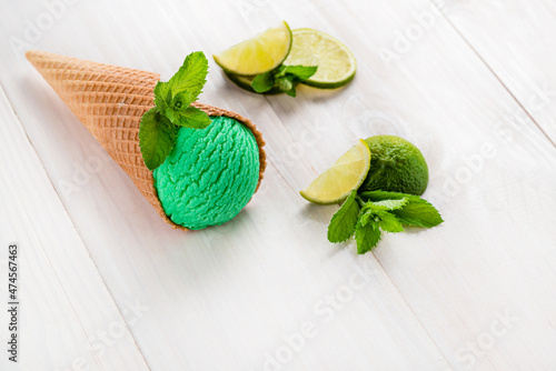 green ice cream with lime and mint in a cone on a white background