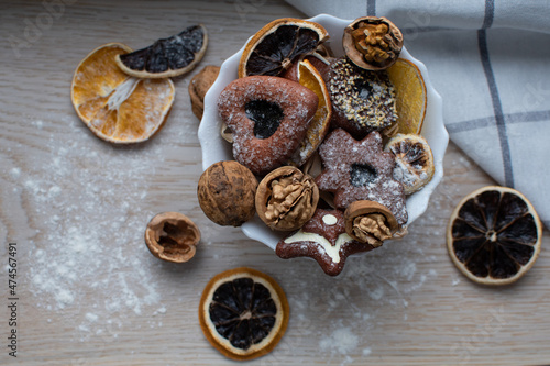 Ginger-sugar cookies are on a white plate, decorated with dry fruits. The orange is dry and the walnut in the shkarloop serves as a decor. Christmas