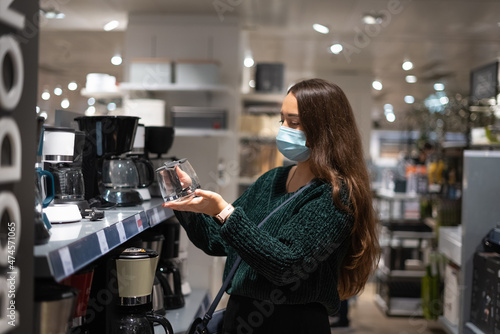 Woman in mask choosing coffee pot