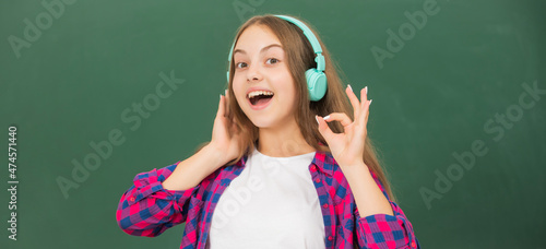 cheerful child listen music in headphones at blackboard, ebook