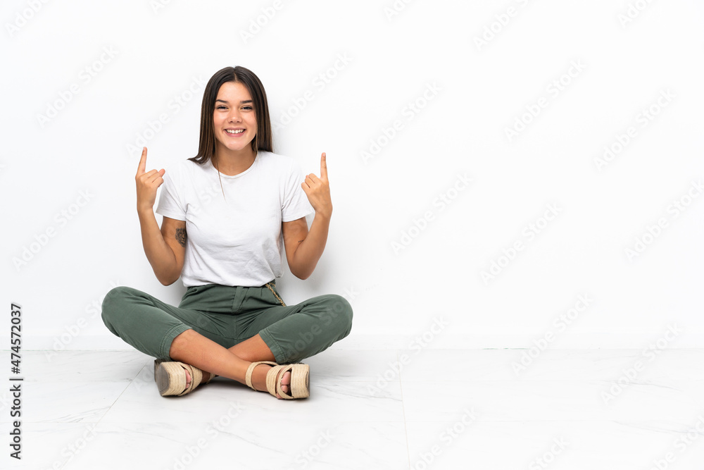 Teenager girl sitting on the floor pointing up a great idea Teenager girl sitting on the floor pointing up a great idea