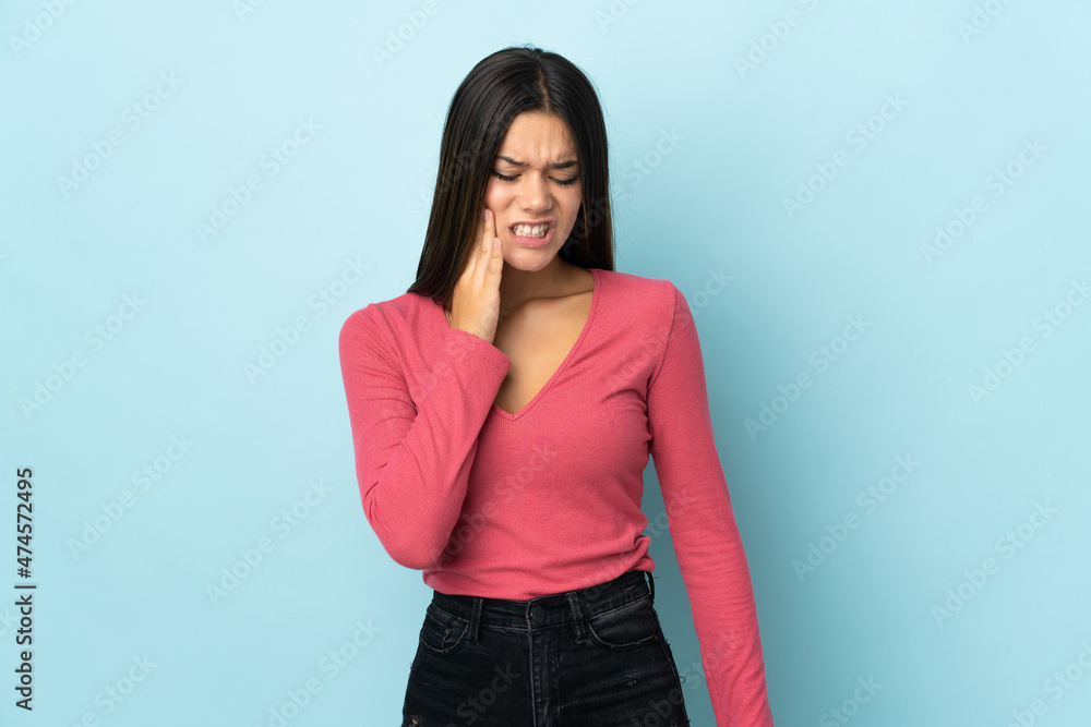 Teenager girl isolated on blue background with toothache Teenager girl isolated on blue background with toothache