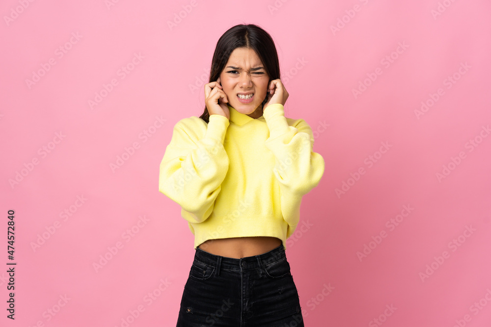 Teenager girl isolated on pink background frustrated and covering ears
