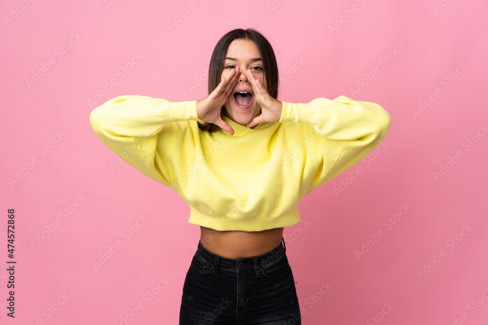 Teenager girl isolated on pink background shouting and announcing something Teenager girl isolated on pink background shouting and announcing something