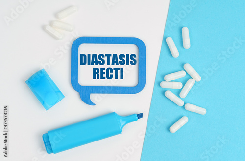On a white and blue table are pills, a marker and a blue plaque with the inscription - Diastasis Recti