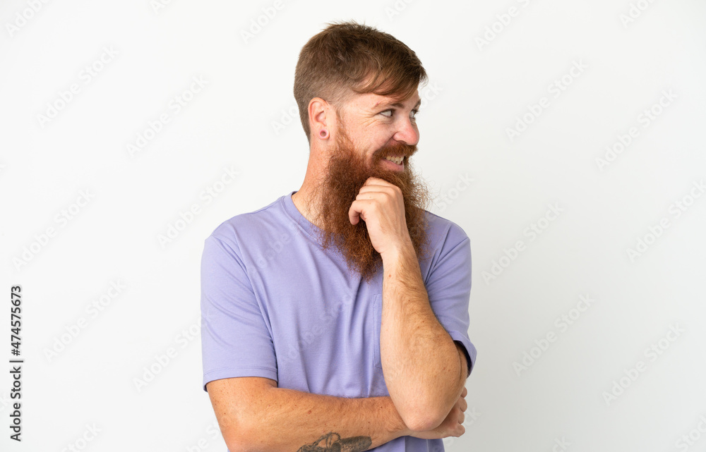 Young reddish caucasian man isolated on white background looking to the side and smiling