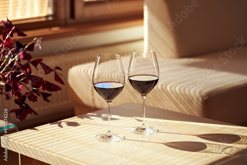 Quadro su tela Two glasses of red wine on a table indoors in sunlight from the window