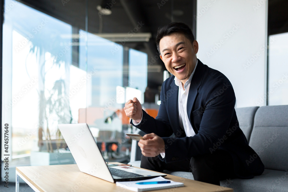 Happy asian businessman transferring credit card, happy and smiling man buying in online store sitting in office Happy asian businessman transferring credit card, happy and smiling man buying in online store sitting in office