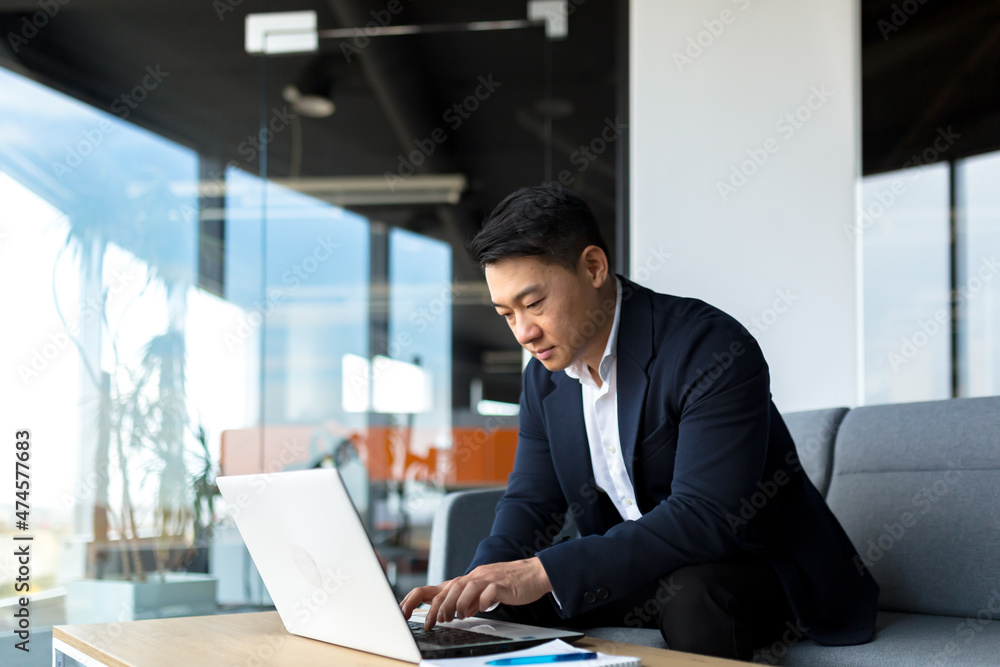 balanced and calm businessman, asian man thinking working at laptop sitting in the office by the window balanced and calm businessman, asian man thinking working at laptop sitting in the office by the window