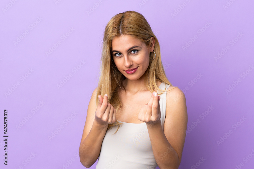 Young Uruguayan blonde woman over isolated background making money gesture but is ruined Young Uruguayan blonde woman over isolated background making money gesture but is ruined