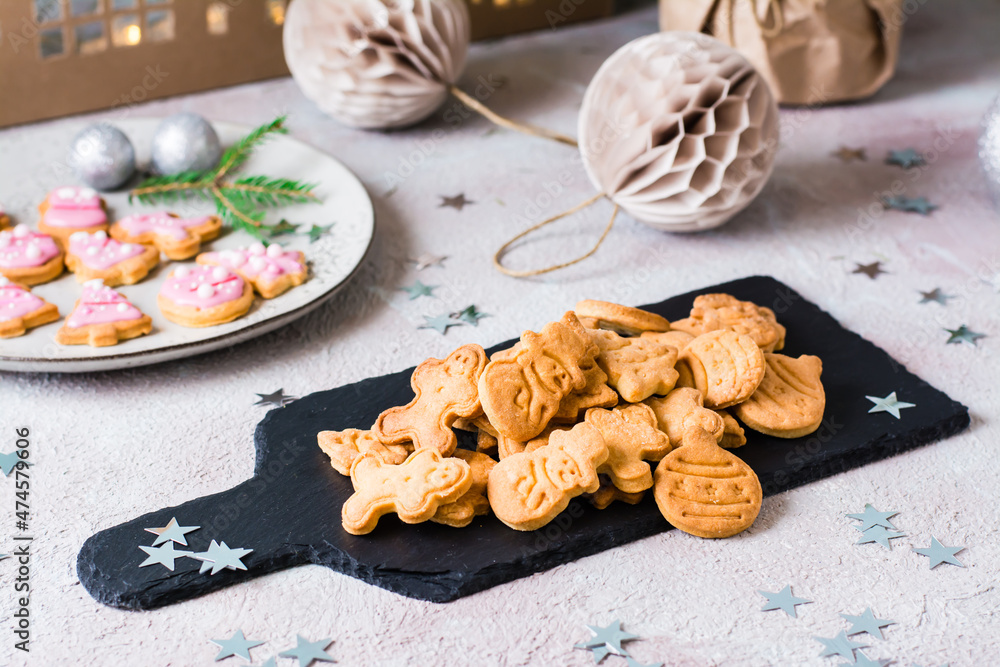 Freshly baked Christmas cookies are piled on a slate on a decorated table. Festive treat