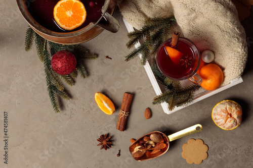 Mulled wine or glegg in a glass with cinnamon and orange, on a wooden tray, with a knitted scarf and fir branches. Top view