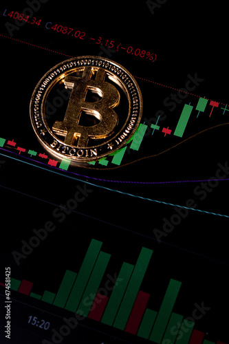 Coin Bitcoin on background cryptocurrency trading chart on computer screen. Digital money, banking, investment, finance and business concept.