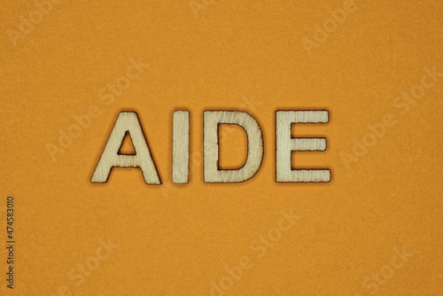 gray word aide made of wooden letters on brown background