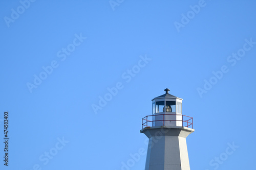 Wallpaper Mural The watch room of a vintage eight-sided lighthouse. The lantern room has a large green bulb. The concrete building is white with a white rail around the gallery deck. The background is a blue sky. Torontodigital.ca