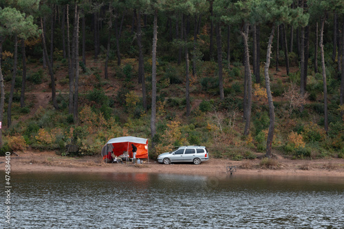 Camping photos. A tent and a car at a viewpoint, overlooking lake in autumn landscape. Adventure holiday. Beautiful, colorful trees reflection to water. Rural scenery.   © burhan
