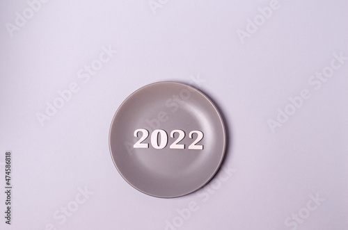 Wooden white numbers 2022 on a plate on a gray background with place for text, copy space.