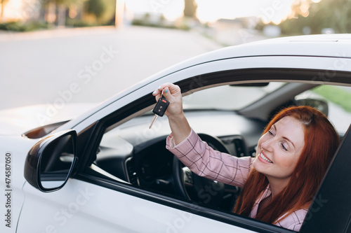 Woman bought first car. Joyful female sitting in new car and shows keys. © MZaitsev