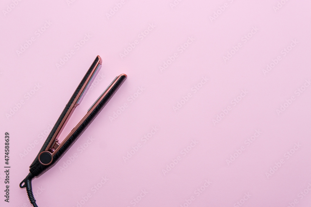 Top view of black hair straightening iron on pink background. Hair care concept Top view of black hair straightening iron on pink background. Hair care concept