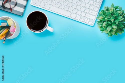 Office desk with computer, eyeglass, Notebook, Cup of coffee on blue background, Top view with copy space, Mock up....