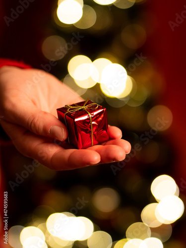 dawać prezent - dłoń trzymająca mały czerwony prezent, prezent świąteczny, święta bożego narodzenia
