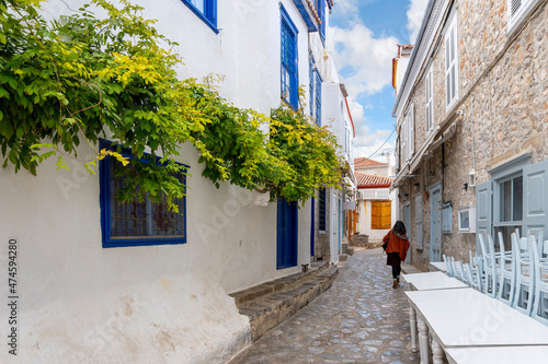 Fototapeta Naklejka Na Ścianę i Meble -  A woman walks through a colorful narrow alley on the island of Hydra, one of the Saronic islands of Southern Greece.