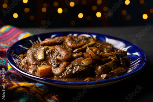 Mexican romeritos with mole sauce and shrimp on a dark background