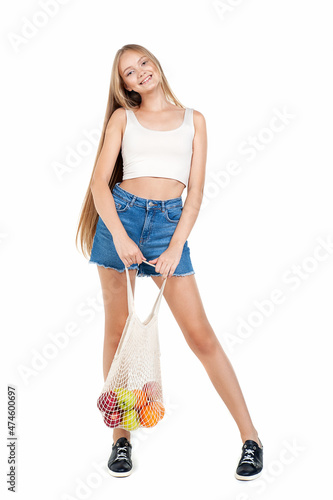 Teenager girl with eco-friendly wicker bag with fruits, on a white background. Eco-friendly concept. Reusable. Wastelessness.