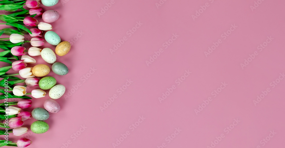 Overhead view of tulip flowers and eggs forming left border on a soft pink background for a happy Easter Day holiday Overhead view of tulip flowers and eggs forming left border on a soft pink background for a happy Easter Day holiday