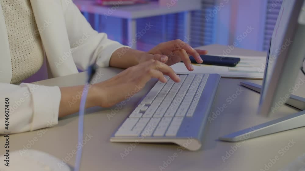 Close-up of female hands typing working with PC keyboard while businesswoman is sitting at desk in dark office. People and technology concept. Close-up of female hands typing working with PC keyboard while businesswoman is sitting at desk in dark office. People and technology concept.