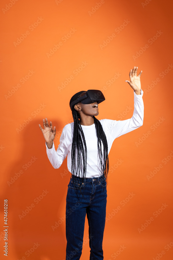 3d technology, virtual reality, entertainment, cyberspace and people concept - Impressed African-American woman in vr-glasses seeing something on orange background with copy space 3d technology, virtual reality, entertainment, cyberspace and people concept - Impressed African-American woman in vr-glasses seeing something on orange background with copy space