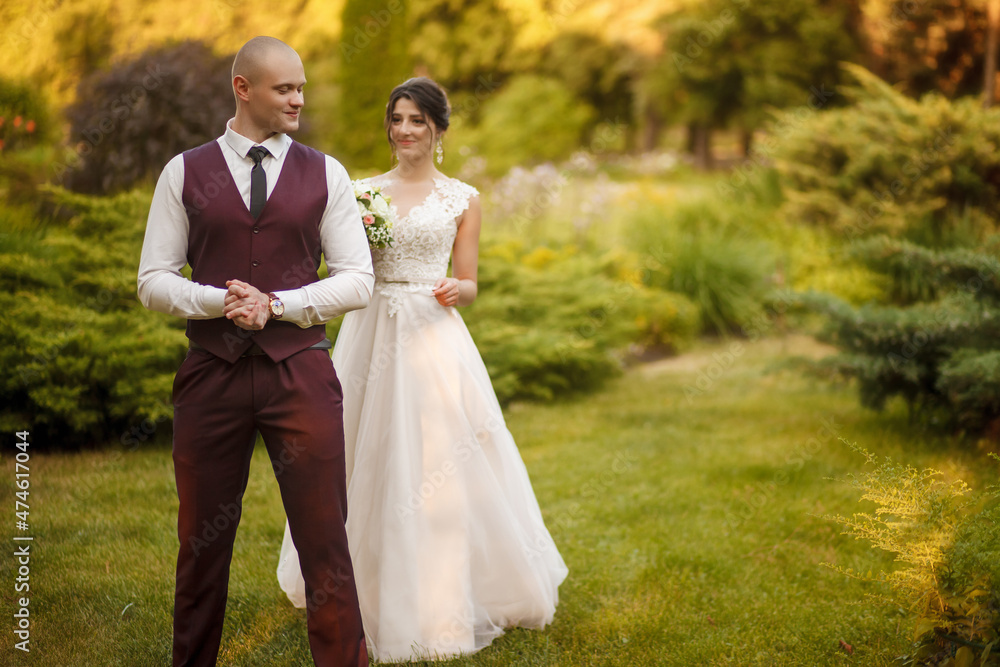Wedding walk of the newlyweds on a warm autumn day. The groom is waiting for his bride in a beautiful green garden. Wedding walk of the bride and groom at sunset. Wedding walk of the newlyweds on a warm autumn day. The groom is waiting for his bride in a beautiful green garden. Wedding walk of the bride and groom at sunset.