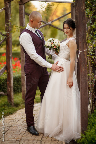 Portrait of a happy wedding couple on their wedding day,beautifully dressed newlyweds tenderly hug while walking in a park, handsome groom gently hugs his bride.