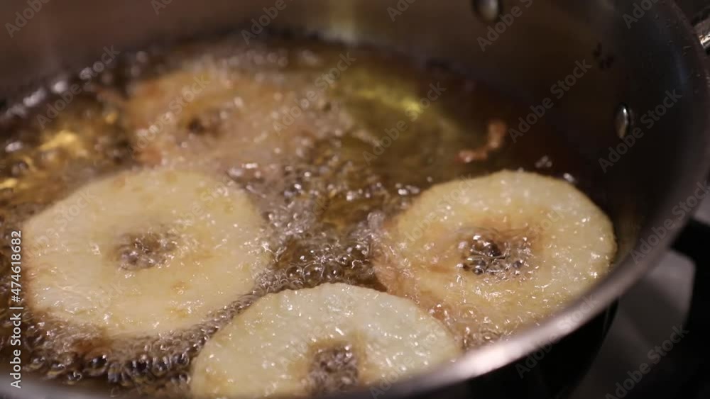 Chef turns over the Apples in the dough, fried in pan in boiling oil Chef turns over the Apples in the dough, fried in pan in boiling oil