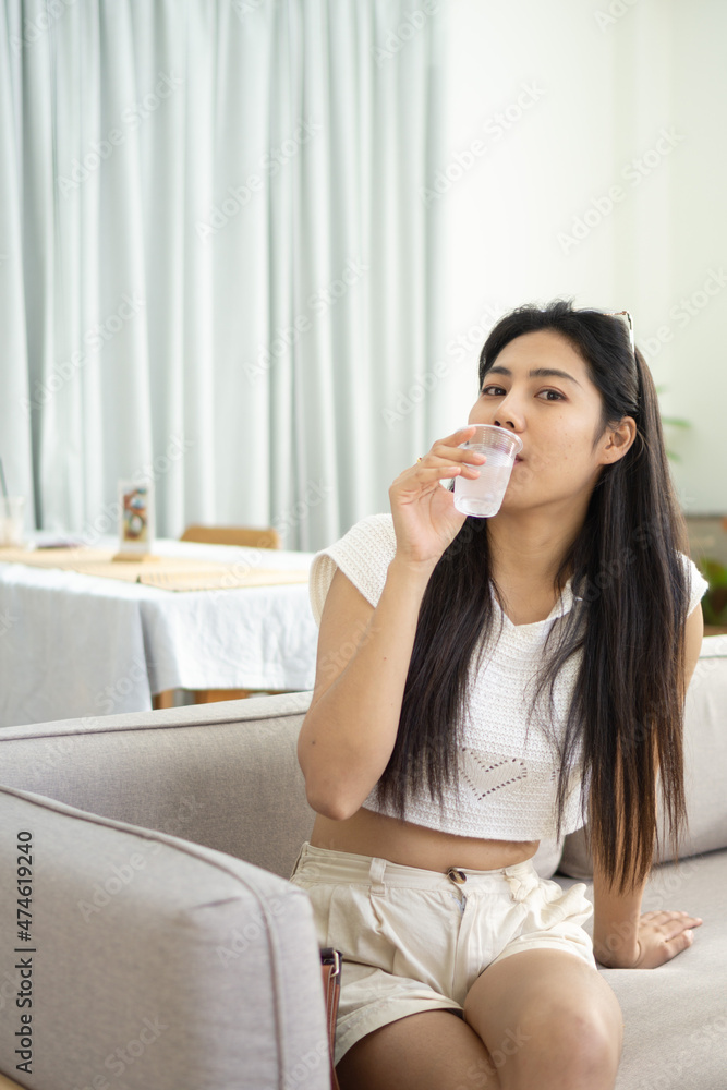portrait of beautiful woman drinking water,sitting on sofa at home portrait of beautiful woman drinking water,sitting on sofa at home