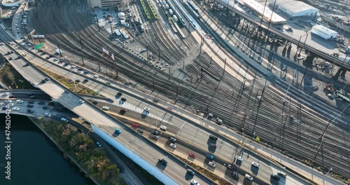 Top down aerial of congested traffic on highways, bridges, roads. Train tracks and station beside river. Infrastructure theme