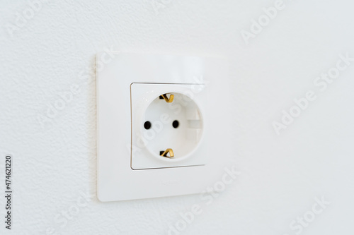 Socket made in a white wall. Socket with grounding. Electricity in the house. A close shot of interior elements.