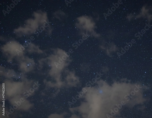 starry night with crisp sky and some clouds with a lot of constellations visible and trees